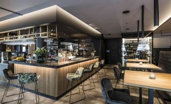 a modern bar with a long wooden counter and several chairs surrounding it , creating an inviting atmosphere at Hotel Post Alpine Cityflair