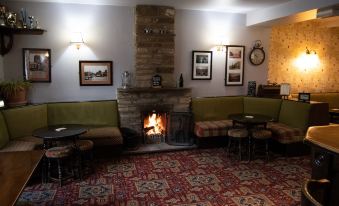 a cozy living room with a fireplace , two couches , and several chairs arranged around it at Black Bull Hotel