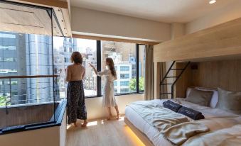 A woman and child are in a bedroom with large windows that overlook other rooms at a luxury hotel at Sakura Cross Hotel Akihabara