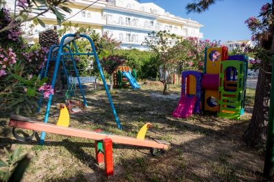 a playground with a variety of play equipment , including a swing , a slide , and a seesaw at Hotel Summery