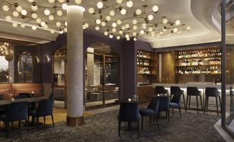 a modern bar with a purple ceiling and various bottles of liquor on display , surrounded by chairs and tables at Sage Melbourne Ringwood