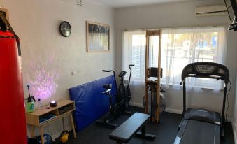a well - equipped home gym with various exercise equipment , including a treadmill , weights , and a bench at Hello Adelaide Motel and Apartments