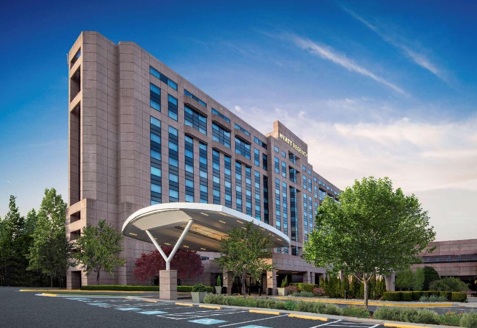 a large building with a curved entrance and trees in front of it under a blue sky at Hyatt Regency Dulles