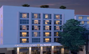 a modern hotel building with multiple floors , surrounded by trees and cars parked in the lot at Hotel Centre Point