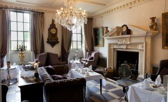 a large , elegant living room with a fireplace , multiple couches , and a dining table , all under the elegant atmosphere of a luxurious interior at Chilston Park Hotel