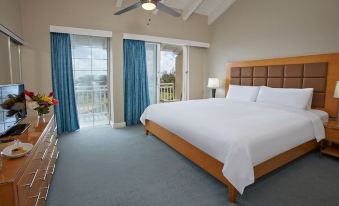 a spacious bedroom with a large bed , white linens , and a view of the ocean at Divi Southwinds Beach Resort