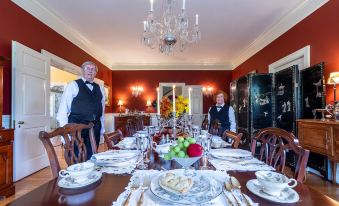 a dining room with a long table set for a formal dinner , featuring a variety of dishes and utensils at Hillcrest Mansion Inn