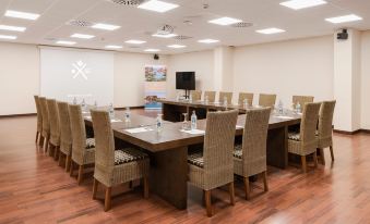 a conference room with a long wooden table , chairs , and a tv mounted on the wall at Barceló Tenerife