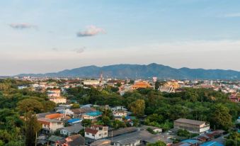 a bird 's eye view of a city with houses and trees , set against a backdrop of mountains at Rattanachol Hotel