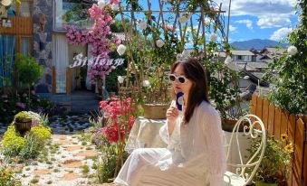 A woman sits on a balcony with her phone in front of her, while another person stands next to her at Lijiang Ancient City Meets Jiaren · White Horse Light Luxury · Snow Mountain View Homestay