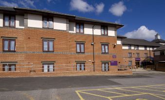 a brick building with multiple windows and a purple sign on the left side , and a street in front of it at Premier Inn Gillingham Business Park