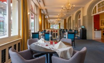 a modern dining room with a table set for two people , complete with chairs and wine glasses at Arenas Resort Victoria-Lauberhorn