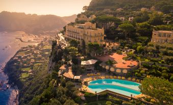 a luxurious resort with a large swimming pool situated on a cliff , surrounded by lush greenery and overlooking the ocean at Hotel Caesar Augustus