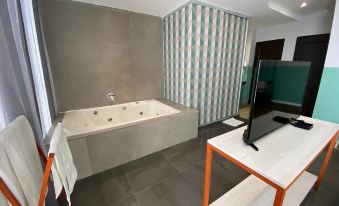 a modern bathroom with a large bathtub , sink , and a tv mounted on the wall at Hotel G