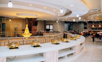 a modern restaurant with a long marble table and gold chandeliers , providing an elegant and inviting atmosphere at Gold Crest Hotel