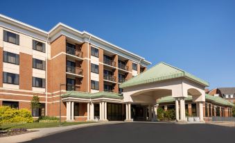 a large hotel building with multiple entrances and a parking lot in front of it at Courtyard Newark-University of Delaware
