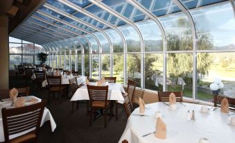 a restaurant with large windows and tables , set for dining under a covered dining area at Fairmont Hot Springs Resort