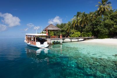 a boat is docked at a pier on a tropical island , with a gazebo and palm trees in the background at Vilamendhoo Island Resort & Spa