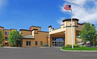 a large , yellow building with an american flag flying in front of it , situated in a parking lot at Oxford Suites Pendleton