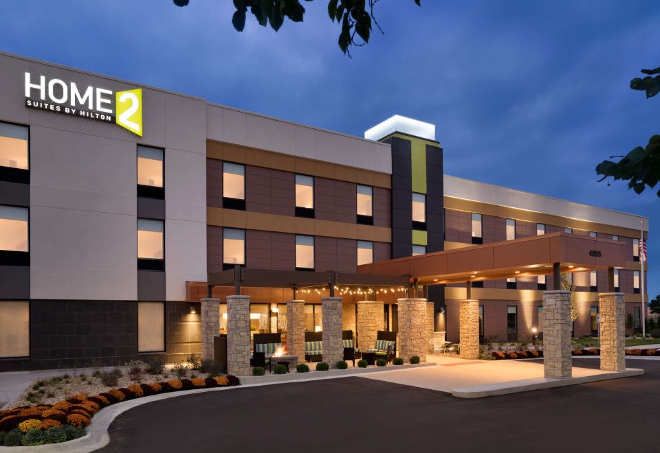 an exterior view of a holiday inn express hotel at night , with a large sign above the entrance at Home2 Suites by Hilton Joliet/Plainfield