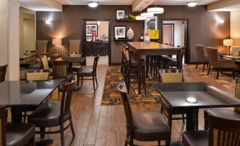 a well - decorated restaurant with various dining tables , chairs , and a tv mounted on the wall at Wingate by Wyndham Steubenville