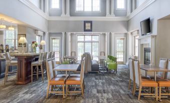 a large dining room with wooden floors , tables , chairs , and couches arranged for a group of people at Homewood Suites by Hilton Olmsted Village (Near Pinehurst, NC)