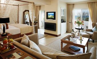 a spacious bedroom with a king - sized bed , a couch , and a flat - screen tv . also a dining table in the room at Vila Vita Parc