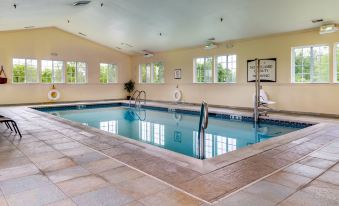 a large indoor swimming pool with a diving board and ladder , surrounded by windows and chairs at Staybridge Suites Philadelphia Valley Forge 422