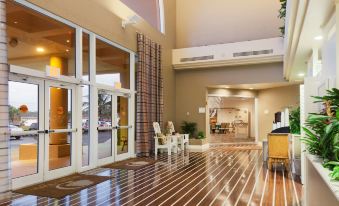 a spacious hotel lobby with high ceilings , large windows , and wooden floors , as well as a reception area and lounge areas at DoubleTree Suites by Hilton Melbourne Beach Oceanfront