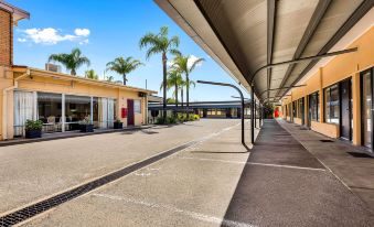 a row of shops with palm trees in the background and a bus stop on the left at Comfort Inn & Suites Manhattan