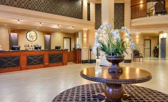 a hotel lobby with a check - in desk , a reception desk , and a vase of flowers on a round table at Grand Hotel at Bridgeport