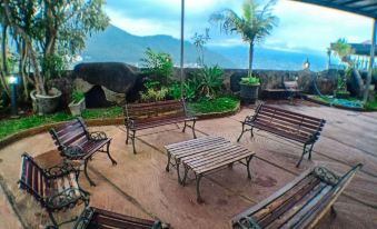 a group of benches and chairs arranged on a patio , surrounded by plants and trees at Seulawah Grand View