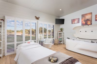 a modern bedroom with white walls , wooden floors , and large windows that offer views of the outdoors at The Swan Valley Retreat