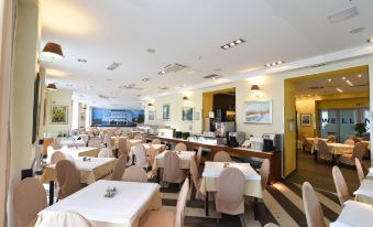 a large , empty restaurant with white tables and chairs , a bar area , and a window at Hotel Park