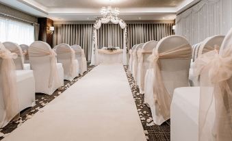 a long white aisle with chairs and a chandelier is set up in a room at Horsley Lodge