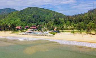 aerial view of a sandy beach near a mountain , with a group of people enjoying their time on the beach at Quynh Vien Resort Ha Tinh