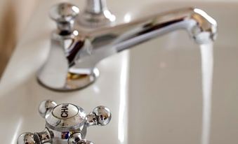 a close - up of a chrome faucet with three handles and a running water droplet from the above at Le Grand Hôtel