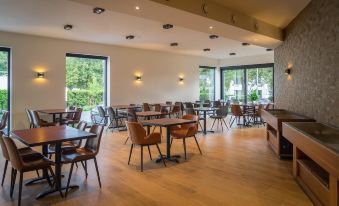 a large dining room with wooden tables and chairs arranged for a group of people to enjoy a meal together at Hotel Huron