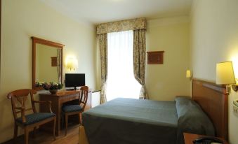 a hotel room with a double bed , a desk , a chair , a television , and a window at Hotel Majestic