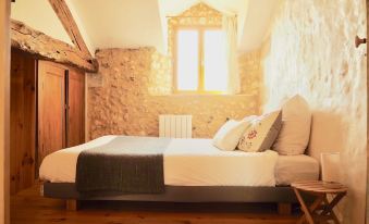 a large bed with a wooden headboard is in a room with stone walls and a window at La Belle Verte