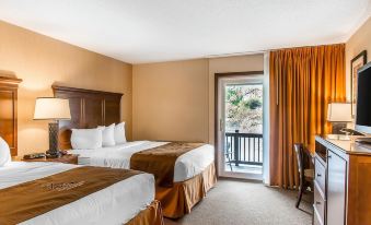 a hotel room with two beds , a chair , and a sliding glass door leading to a balcony at The Black Swan Lee - Lenox, Ascend Hotel Collection