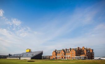 a large , orange building with a yellow logo is surrounded by a green field and blue sky at Marine Troon