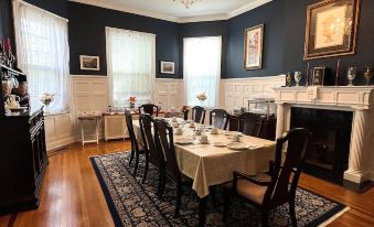 a dining room with a large table set for a meal , surrounded by chairs and a fireplace at 1912 Bed and Breakfast