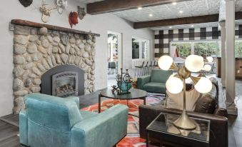 a cozy living room with a stone fireplace , two couches , and a television mounted on the wall at The Creekstone