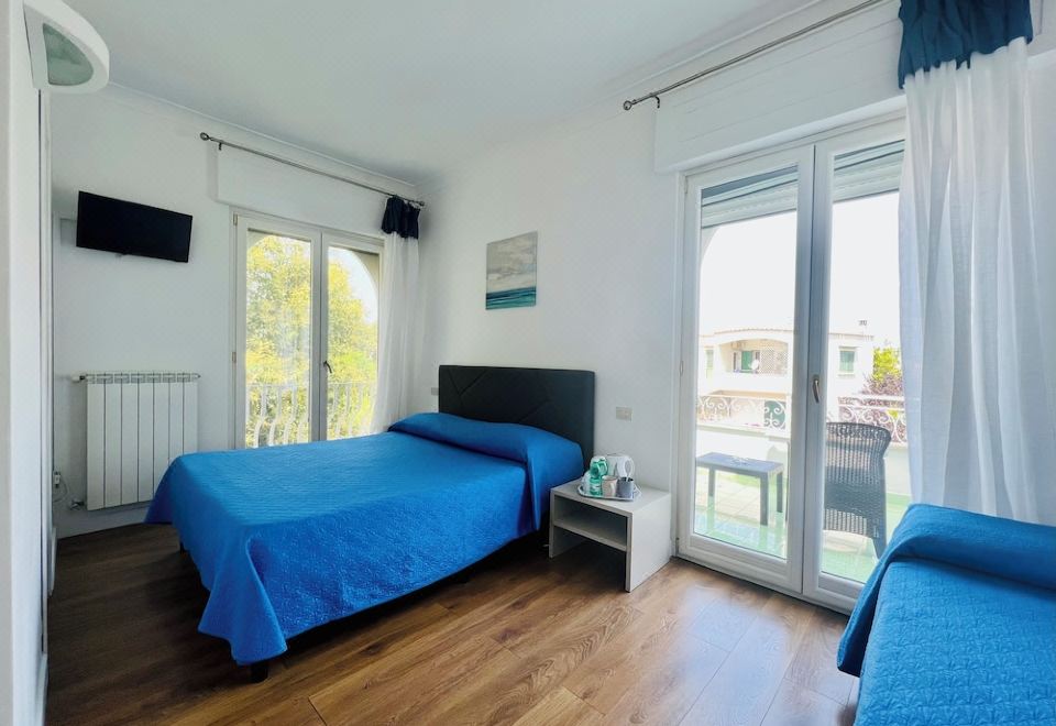 a bedroom with a blue bed , two chairs , and a sliding glass door leading to a balcony at YourHome - Villa Sorrento