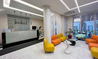 a modern hotel lobby with a white marble floor and colorful furniture , including chairs and couches at Hotel Joli