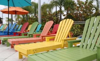 a colorful array of lounge chairs and umbrellas on a patio with palm trees in the background at Legoland Beach Retreat