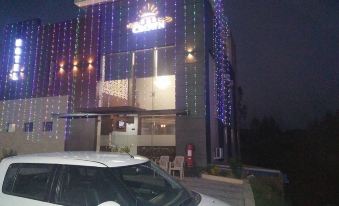 a white car is parked in front of a building with colorful lights and a sign at The Crown