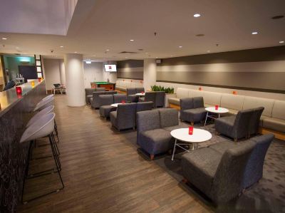 a modern waiting room with gray couches , white tables , and red balloons , as well as billiard tables at Ibis Melbourne Hotel and Apartments