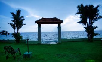 a gazebo overlooking the ocean , with a stone pillar and a lantern placed near the water 's edge at Paradise Resorts